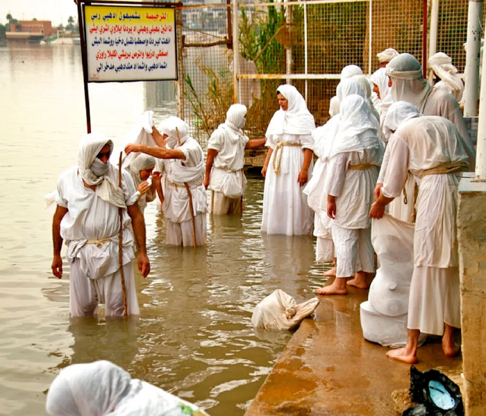 Mandaean people performing a Mandaean baptism ritual in the river, showcasing Mandaean religious traditions and attire.